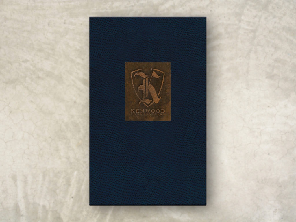 Blue ostrich leather menu cover with a copper inset and embossed logo